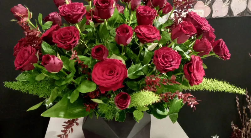 Luxurious red roses in geometric black vase with mixed greenery