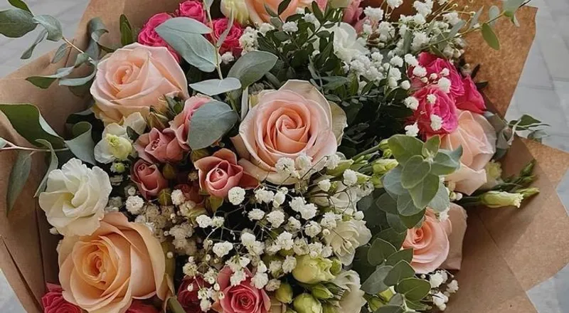 Mixed peach, pink and white roses with eucalyptus in kraft paper