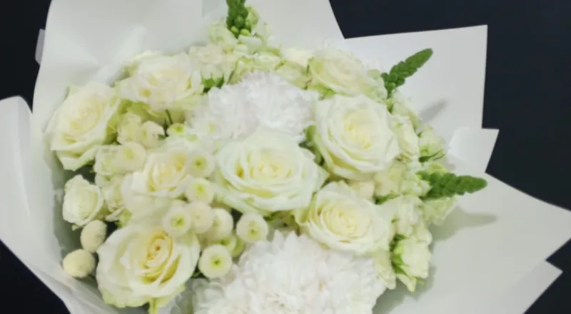 White roses, chrysanthemums and snapdragons in pristine white wrapper