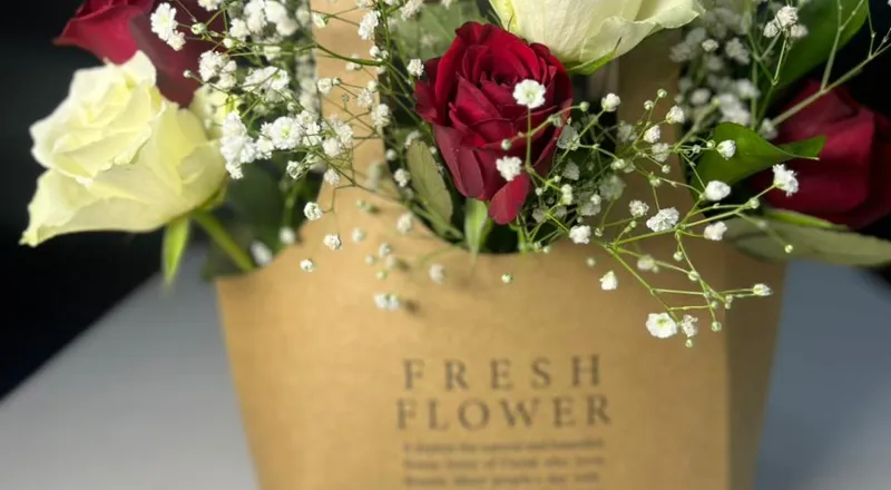 Red and white roses with baby's breath in kraft paper carrier bag